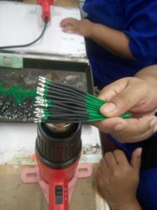 Protecting wires with heat shrink tubing in a manufacturing process with a heat gun.